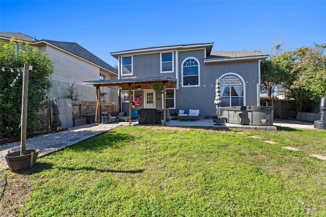 rear view of property with an outdoor hangout area, a patio area, a hot tub, and a lawn