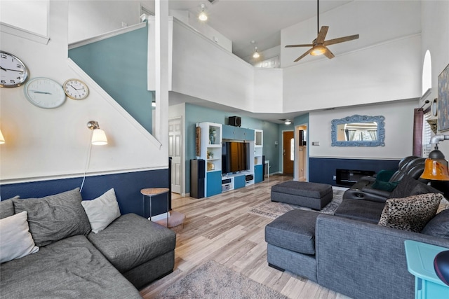 living room with hardwood / wood-style flooring, ceiling fan, and a high ceiling