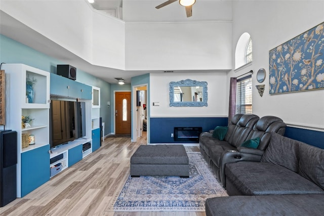 living room featuring a high ceiling, wood-type flooring, and ceiling fan