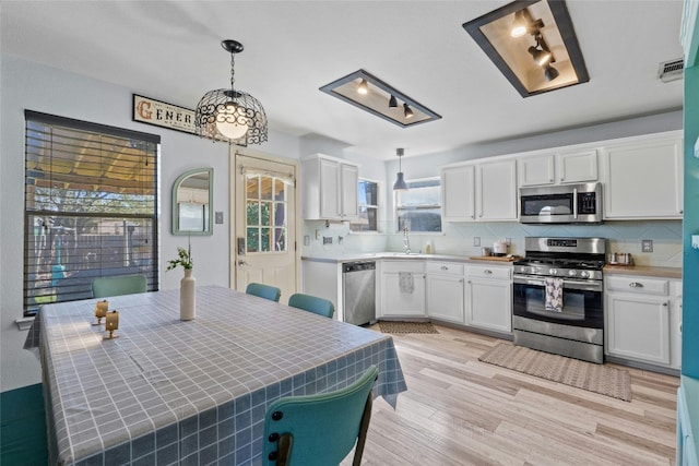 kitchen featuring white cabinetry, stainless steel appliances, decorative light fixtures, and backsplash