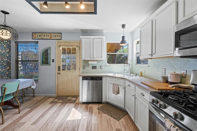 kitchen with pendant lighting, stainless steel appliances, sink, and white cabinets