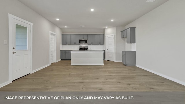 kitchen featuring stainless steel appliances, a kitchen island, gray cabinets, and light hardwood / wood-style floors