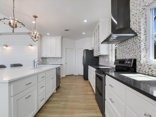 kitchen featuring white cabinetry, wall chimney range hood, pendant lighting, and appliances with stainless steel finishes