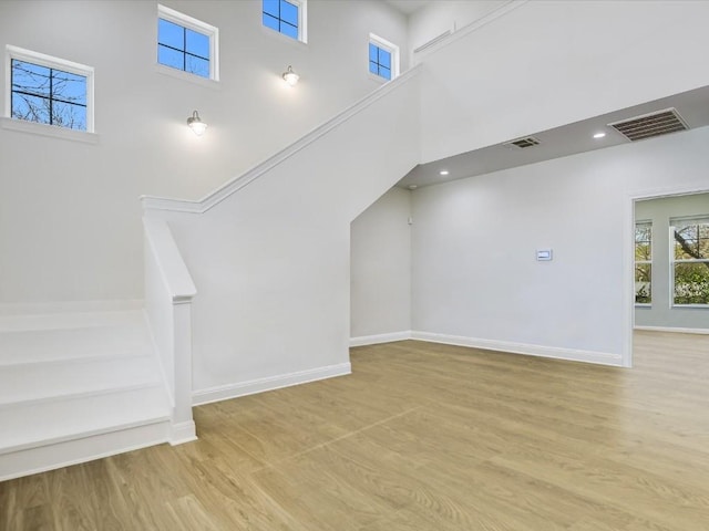 additional living space with light hardwood / wood-style flooring and a high ceiling