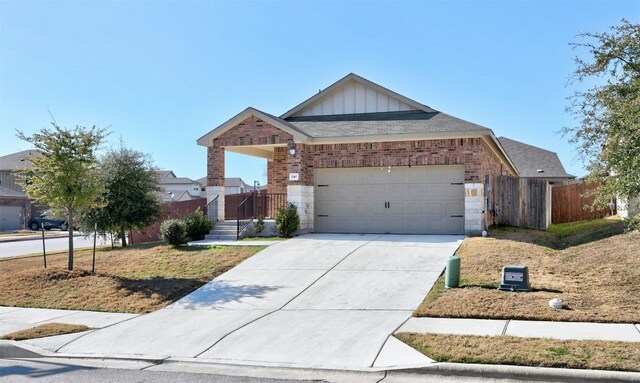 view of front of home with fence, board and batten siding, concrete driveway, a garage, and brick siding