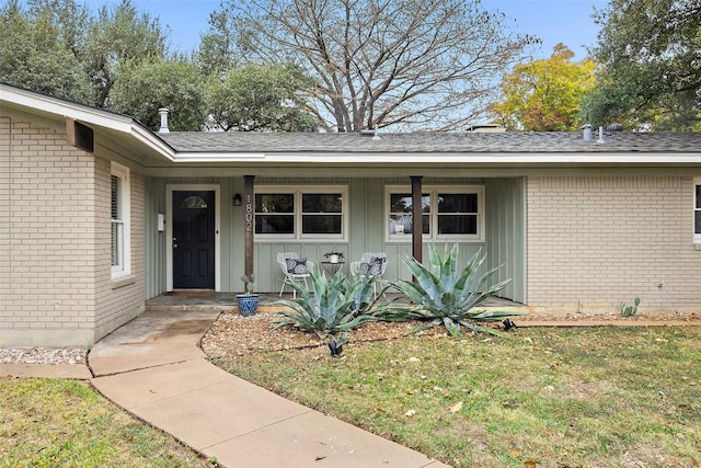 property entrance featuring board and batten siding, brick siding, and a yard