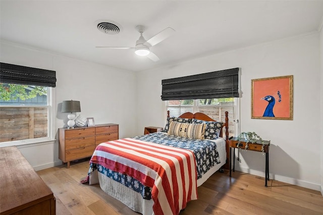 bedroom with ceiling fan, light wood-style flooring, visible vents, and baseboards