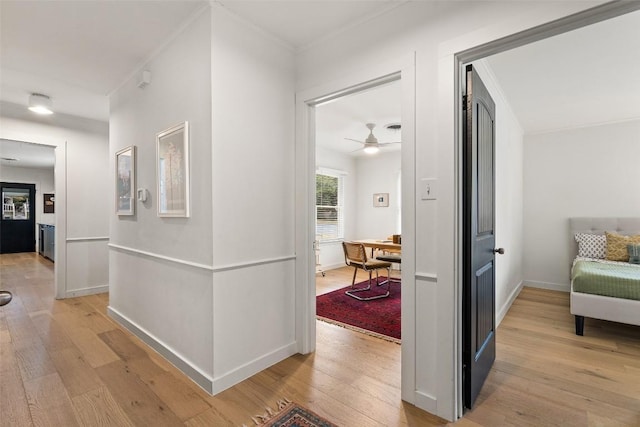 corridor with ornamental molding and light wood-type flooring