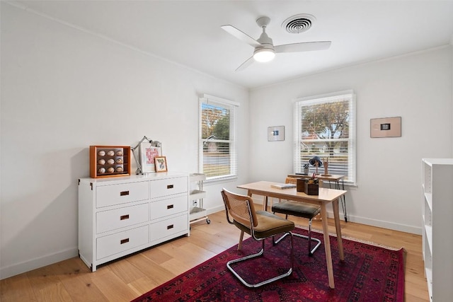 office area with light wood finished floors, visible vents, baseboards, and a ceiling fan