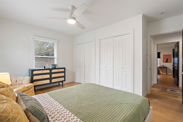 bedroom with multiple closets, wood-type flooring, ceiling fan, and crown molding