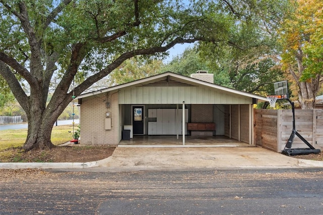 view of front facade with driveway, brick siding, and a chimney