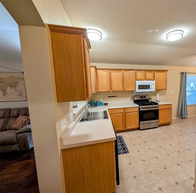 kitchen featuring stainless steel range with gas stovetop, sink, and a textured ceiling