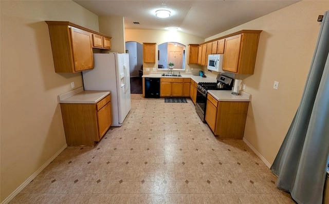 kitchen with sink, white appliances, and vaulted ceiling