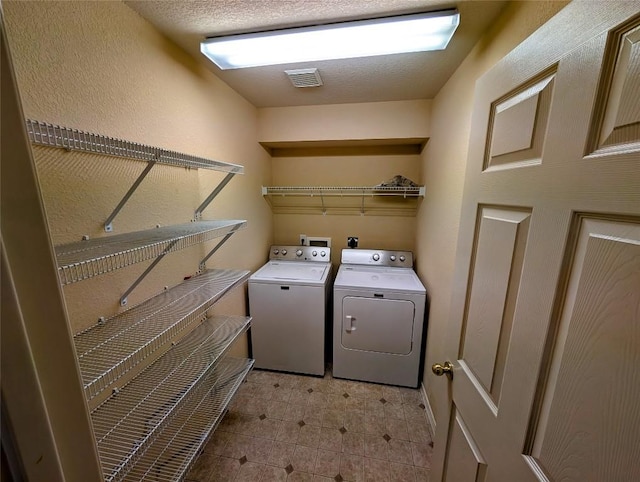 laundry room featuring washer and clothes dryer and a textured ceiling