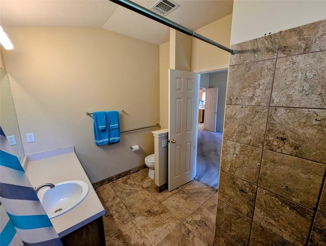 bathroom featuring vanity, vaulted ceiling, and toilet