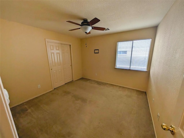 unfurnished bedroom featuring ceiling fan, carpet floors, a textured ceiling, and a closet