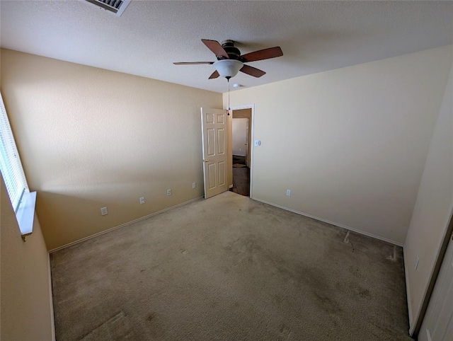 carpeted empty room with ceiling fan and a textured ceiling