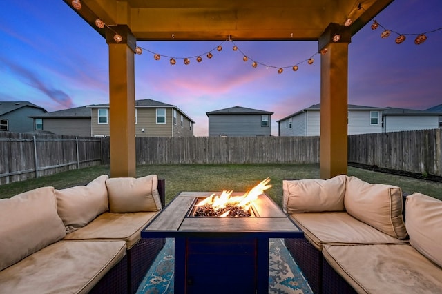 patio terrace at dusk featuring an outdoor living space with a fire pit and a lawn