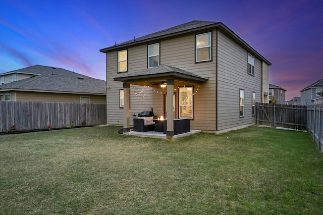 back house at dusk with a patio, outdoor lounge area, and a lawn