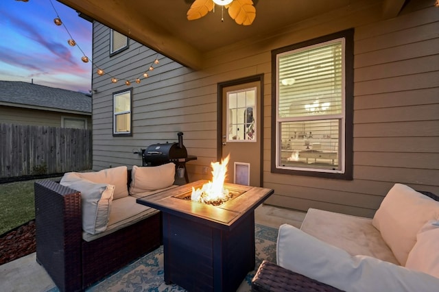 patio terrace at dusk featuring ceiling fan, grilling area, and an outdoor living space with a fire pit