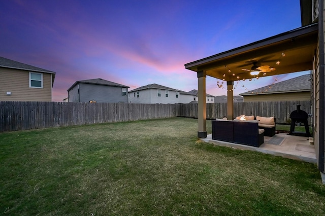 yard at dusk featuring ceiling fan, outdoor lounge area, and a patio area