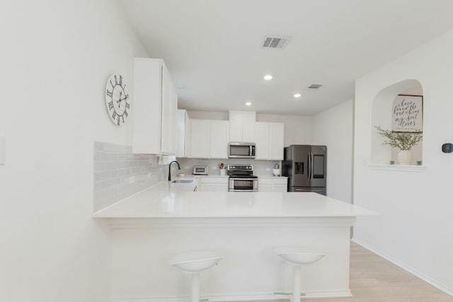 kitchen with sink, kitchen peninsula, white cabinets, and appliances with stainless steel finishes