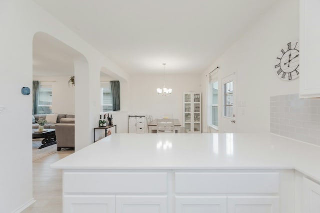 kitchen featuring an inviting chandelier, backsplash, hanging light fixtures, and white cabinets