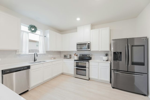 kitchen with stainless steel appliances, tasteful backsplash, sink, and white cabinets