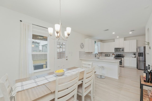 dining area featuring sink, light hardwood / wood-style flooring, and a chandelier