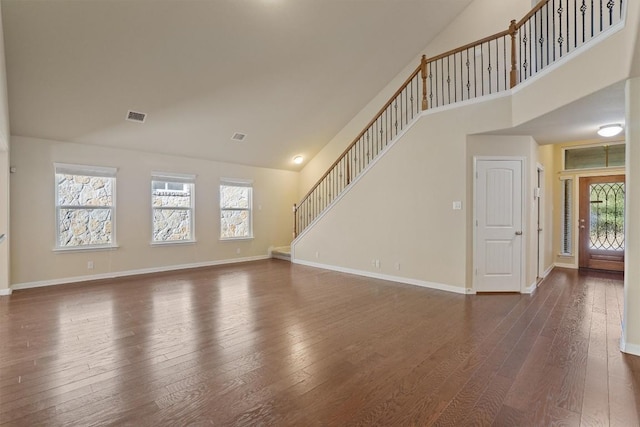 unfurnished living room with dark wood-type flooring and high vaulted ceiling