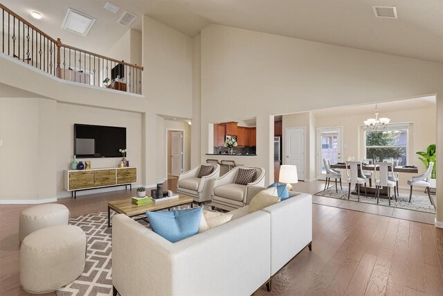 living room featuring wood-type flooring, a chandelier, and vaulted ceiling