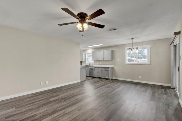 unfurnished living room with sink, ceiling fan with notable chandelier, and dark hardwood / wood-style flooring