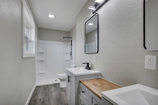 bathroom featuring vanity, hardwood / wood-style floors, toilet, and a shower