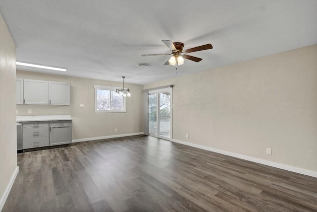 unfurnished living room with dark hardwood / wood-style flooring and ceiling fan with notable chandelier