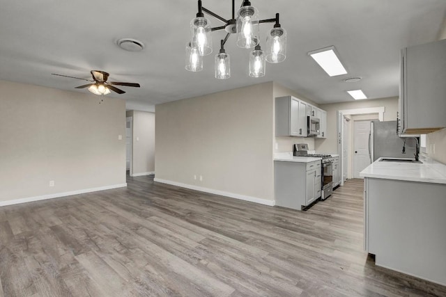 kitchen with sink, gray cabinets, ceiling fan, stainless steel appliances, and light wood-type flooring