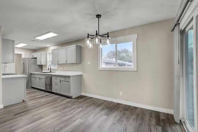 kitchen featuring decorative light fixtures, sink, gray cabinetry, light hardwood / wood-style floors, and stainless steel appliances