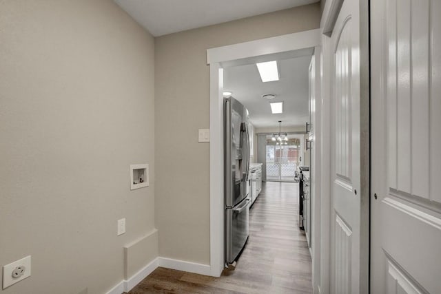 corridor with light hardwood / wood-style floors and a chandelier