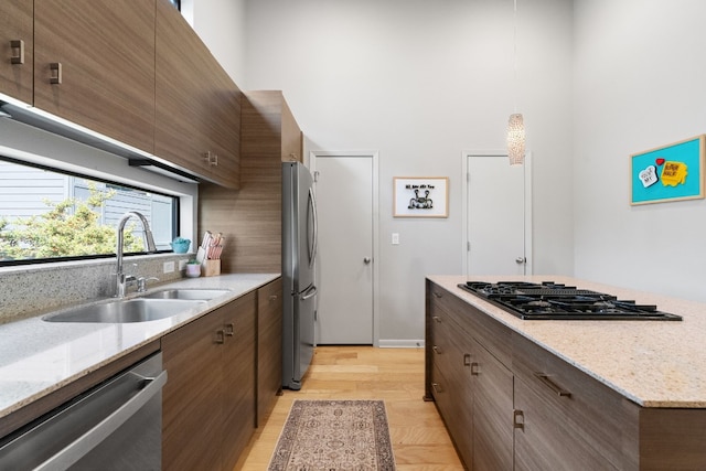 kitchen with stainless steel appliances, a high ceiling, sink, and pendant lighting