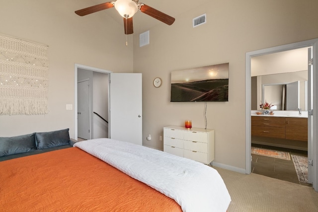 carpeted bedroom featuring ceiling fan, ensuite bathroom, and a high ceiling