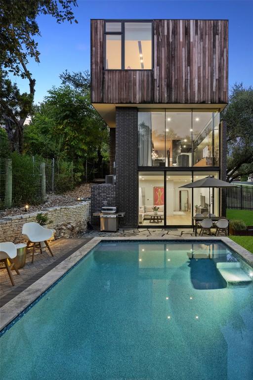 back house at dusk with a fenced in pool and a patio area