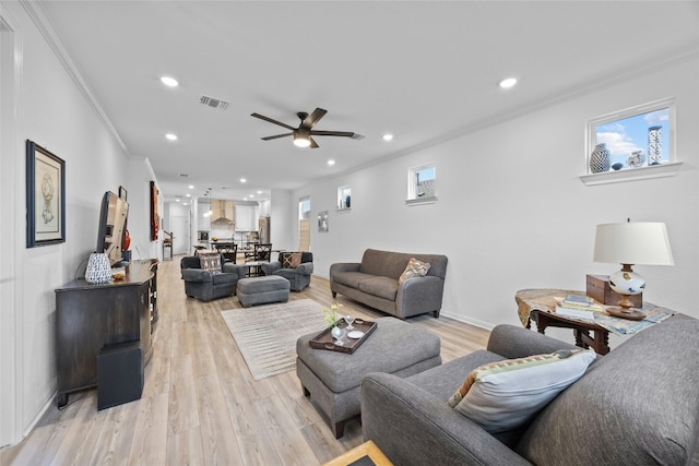 living room with crown molding, ceiling fan, and light hardwood / wood-style flooring