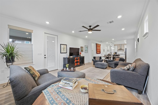 living room featuring crown molding, ceiling fan, and light wood-type flooring