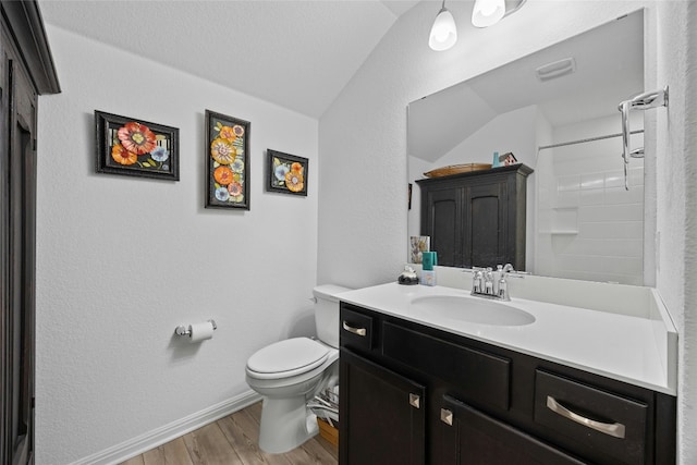 bathroom with vaulted ceiling, hardwood / wood-style flooring, vanity, walk in shower, and toilet