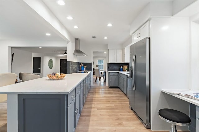 kitchen with light countertops, appliances with stainless steel finishes, gray cabinets, wall chimney exhaust hood, and tasteful backsplash