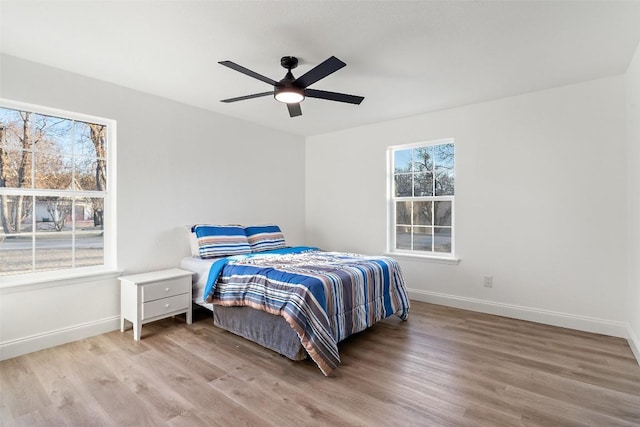 bedroom featuring a ceiling fan, baseboards, and wood finished floors