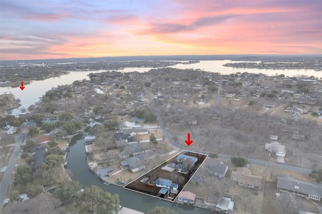 aerial view at dusk featuring a water view