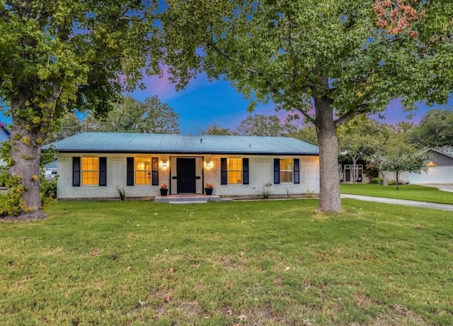 ranch-style home featuring metal roof, a yard, and brick siding