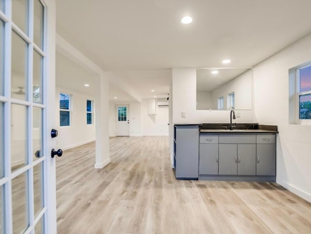 kitchen featuring recessed lighting, gray cabinets, a sink, light wood-type flooring, and baseboards