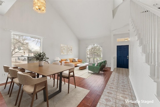 dining area with an inviting chandelier, hardwood / wood-style flooring, and high vaulted ceiling