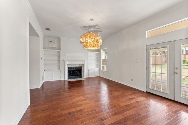 unfurnished living room featuring ornamental molding, dark hardwood / wood-style floors, a chandelier, and a tile fireplace